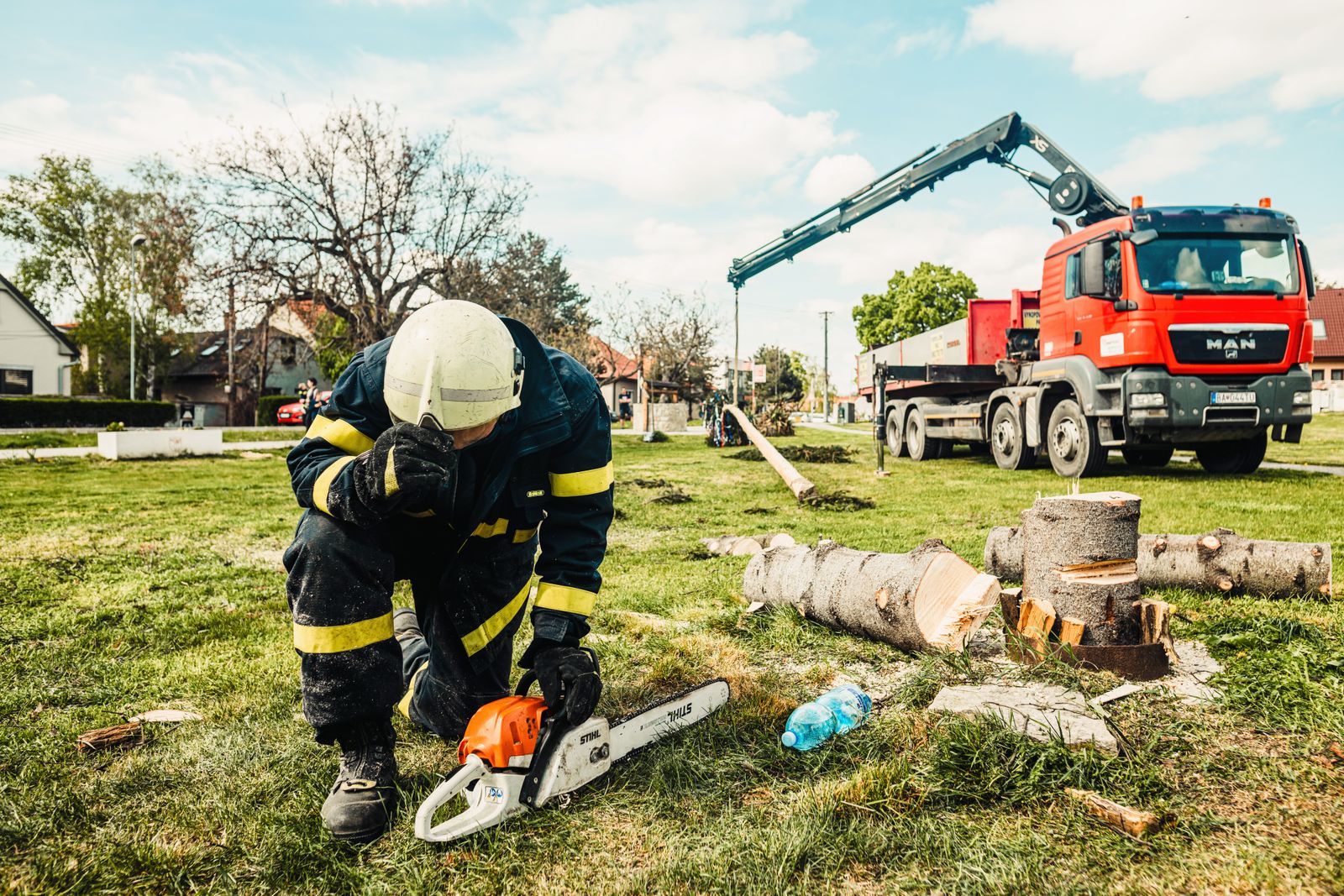Crew member with chainsaw beside a crane truck